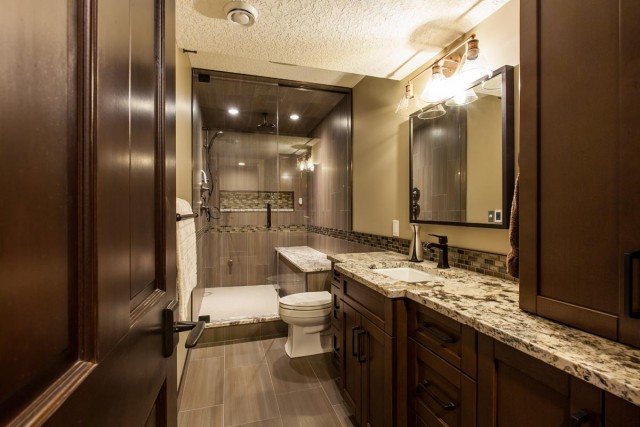 Modern bathroom interior in marble countertop and shower booth surrounded by brown colour closets and door