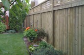 Wooden fence with the check pattern on the top placing next to little garden with flower and plants