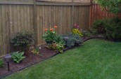 Wooden fence with the check pattern on the top placing next to little garden with flower and plants
