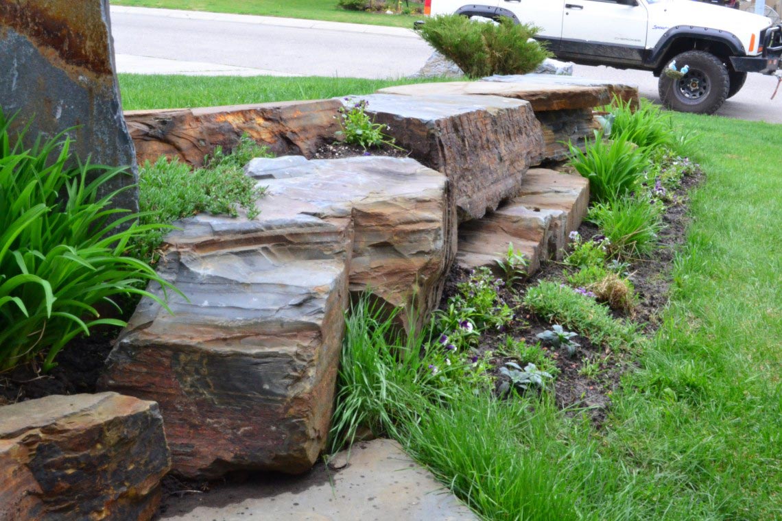 Beautiful brown stoneworks placed on the front yard area with small plants