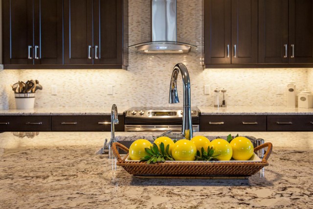 Modern Kitchen Interior in black closets and kitchen island with marble countertop and yellow round fruit ornaments