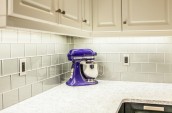 Modern Kitchen Interior deep purple blender is sitting on the marble countertop and light grey tiles on the wall and white closet