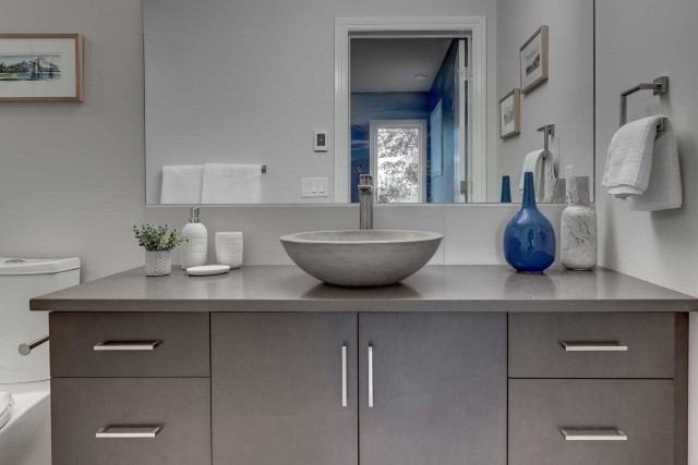 marble bowl shaped basin with empty vases to the right and large rectangular mirror above