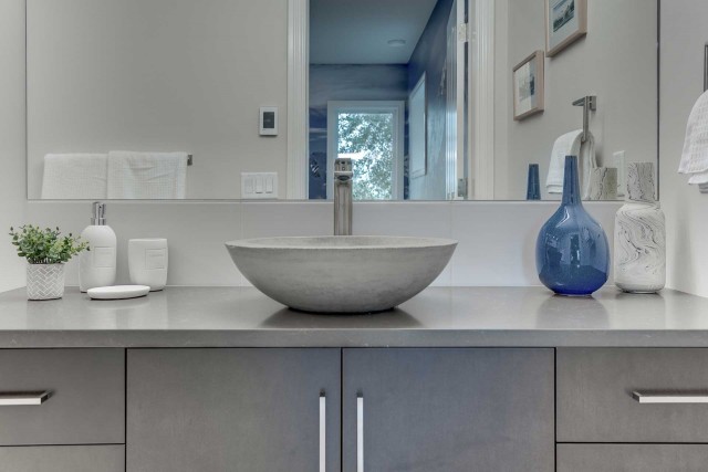 marble bowl shaped basin with empty vases to the right and large rectangular mirror above