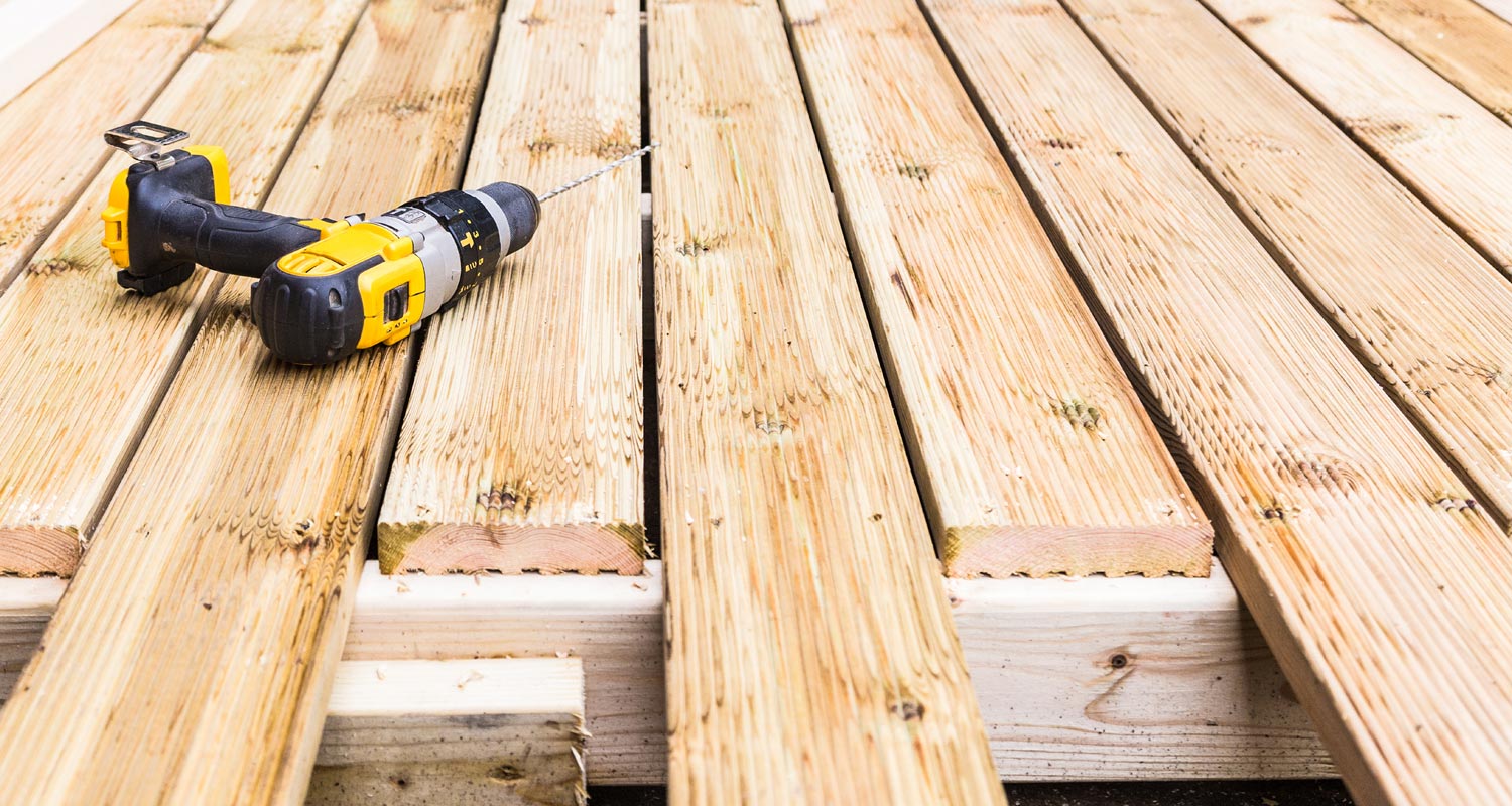 A drill placed on the top of wooden deck construction area