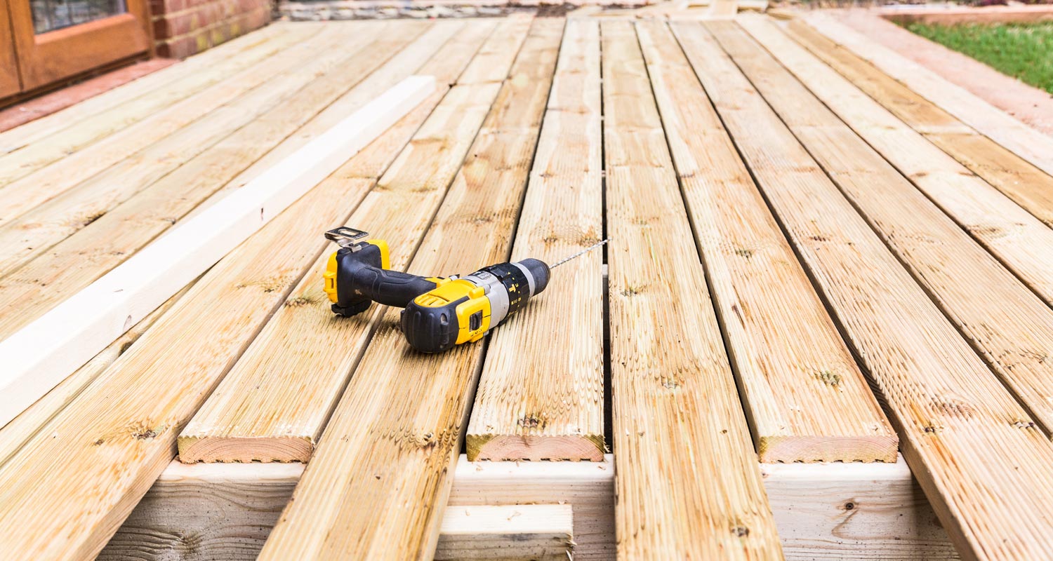 A drill placed on the top of wooden deck construction area