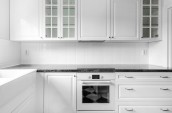 Modern simple minimalistic kitchen interior in white closets and black marble countertop