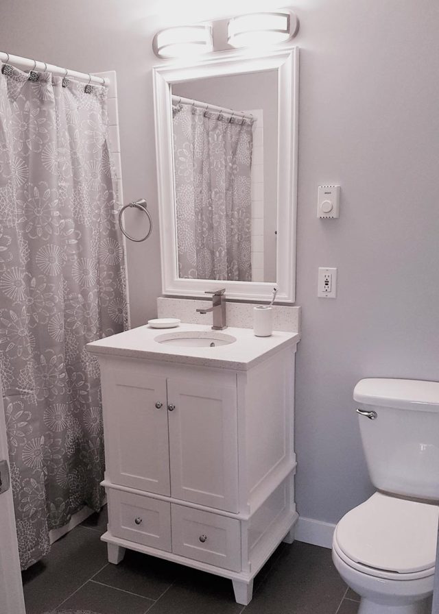 bathroom with closed shower curtain to the left, basin/mirror in the centre and toilet to the right