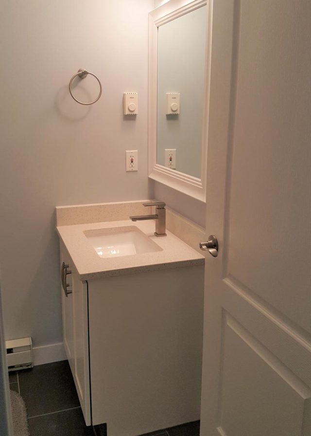 basin in corner of bathroom with towel ring on wall to the left