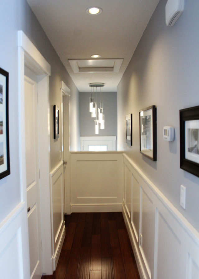 hallway with wooden floor and framed images hanging on wall