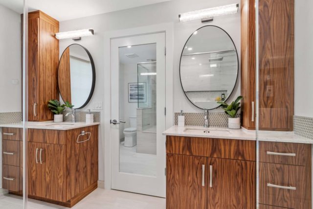 bathroom with wood veneer cabinet and round mirror above basin