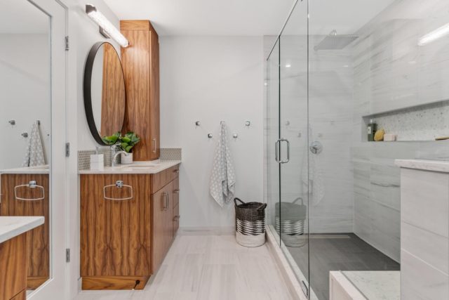 bathroom with wood veneer cabinet and round mirror above basin