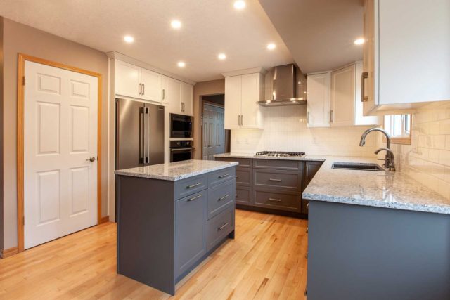 kitchen with double sink, wooden floors and large windows showing gas hob, workstation island, oven and fridge/freezer