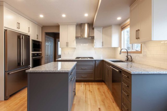 kitchen with double sink, wooden floors and large windows showing gas hob, workstation island, oven and fridge/freezer